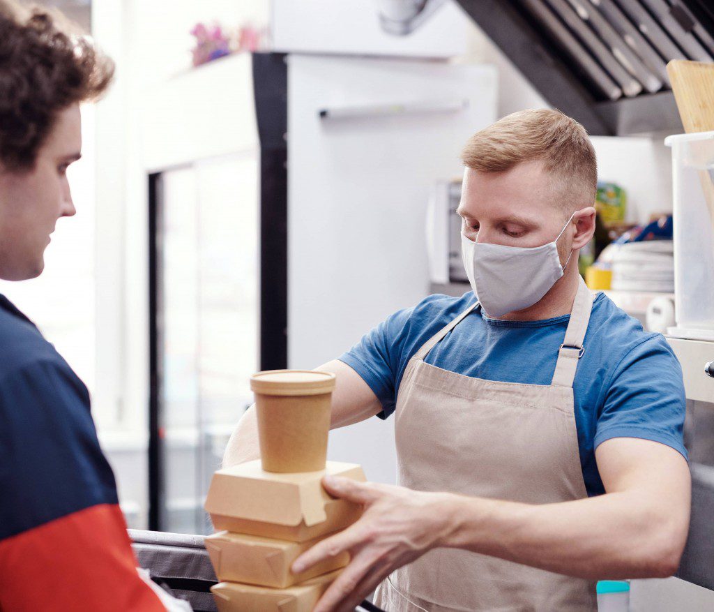 man wearing a face mask putting food